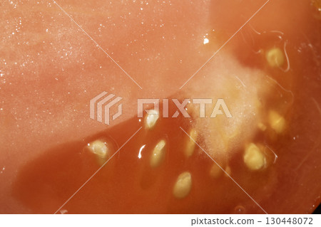 Abstract Tomato Slice Cut in half showing seeds on White Background 130448072