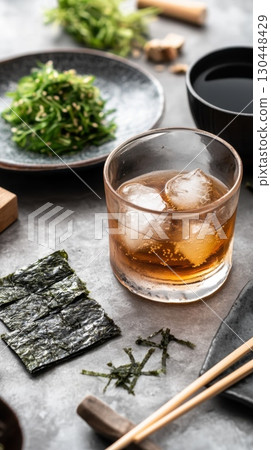 Refreshing glass of iced tea with seaweed salad and nori sheets on stone table 130448429