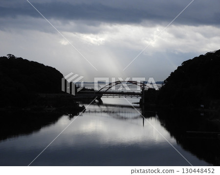 Silhouette of a bridge floating in the light of a cloudy sky 130448452