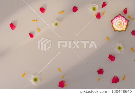 Single Diwali candle surrounded by flower petals for festive decor 130448640