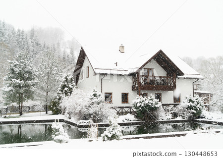 Charming winter house covered in snow creates a cozy atmosphere for holiday relaxation Charming winter house covered in snow creates a cozy atmosphere for holiday relaxation 130448653