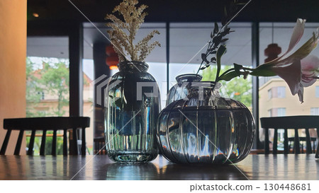Decorative glass vases with flowers on a wooden table in a cozy urban setting Decorative glass vases with flowers on a wooden table in a cozy urban setting 130448681