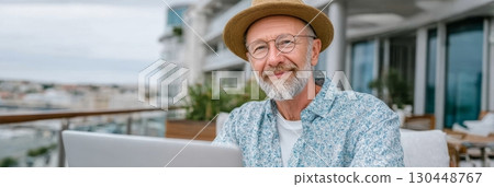 Older professional enjoys remote work at a terrace cafe, highlighting active aging and the ageless workforce 130448767