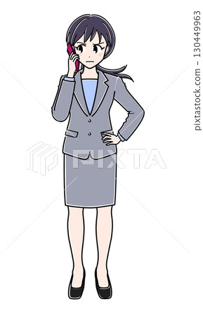 A suit-wearing office lady (full body) standing with a suspicious look on her face and a smartphone to her ear 130449963