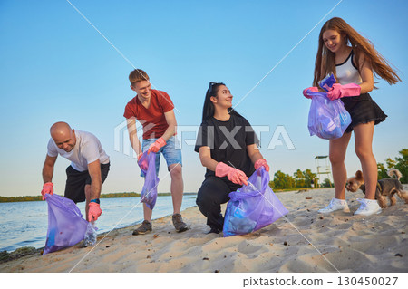 Parents and kids cleaning beach together with gloves and eco bags 130450027
