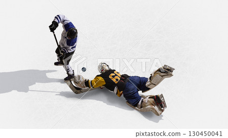 Overhead hockey goalkeeper in yellow jersey diving toward puck against rival 130450041