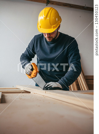 Focused carpenter cutting wood indoors, craftsmanship in action 130450123