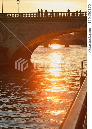 A sunset reflected on the Seine River near the Ile de la Cité in Paris, with a bridge silhouette (photographed on August 17, 2025) 130450170