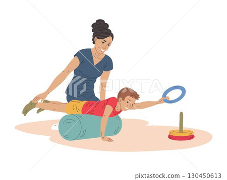 Physiotherapist helps boy on therapy roller reaching toy pyramid 130450613