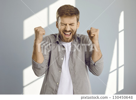 Portrait of young man celebrating success or clenching fists with anger and screaming Portrait of young man celebrating success or clenching fists with anger and screaming 130450648