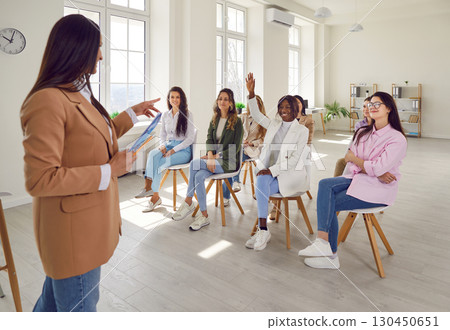Young African American woman puts her hand up to ask a question at a business training class 130450651