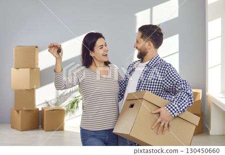 Happy young family couple looking at each other, showing keys to camera 130450660