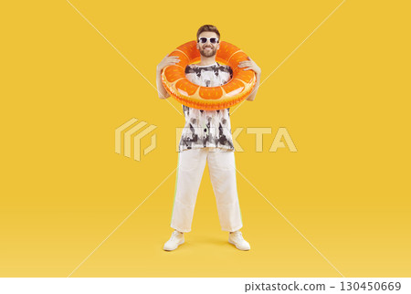Happy young man wearing casual summer holiday clothes, sunglasses and beach ring Happy young man wearing casual summer holiday clothes, sunglasses and beach ring 130450669