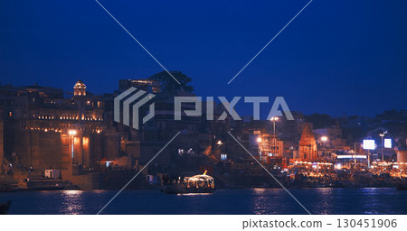 Varanasi, Uttar Pradesh, India. Boats floating near Rana Mahal Ghat, Darbhanga Ghat and Dashashwamedh Ghat in night time illumination lights. Cinematic Camera movement moving along riverbank Varanasi, Uttar Pradesh, India. Boats floating near Rana Mahal Ghat, Darbhanga Ghat and Dashashwamedh Ghat in night time illumination lights. Cinematic Camera movement moving along riverbank 130451906