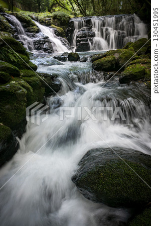 A waterfall leading to the Kikuchi Gorge with a clear stream flowing through nature 130451995