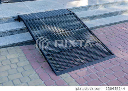 A metal ramp at the building entrance improves mobility and accessibility for individuals with disabilities 130452244