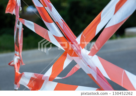 Caution tape is stretched across a road, signaling ongoing construction or maintenance in a quiet neighborhood setting 130452262