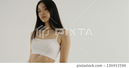 Young woman in white crop top posing indoors with minimal clean fashion style 130453590