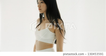 Young woman in white crop top posing indoors with minimal clean fashion style 130453591