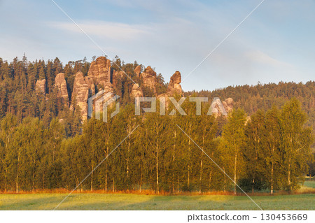 Adrspach-Teplice Rocks, sandstone formations in Hradec Kralove Region in the Czech Republic, Europe. A picturesque scene of sandstone formations rising above a forest, under a soft, muted sky at dawn. 130453669