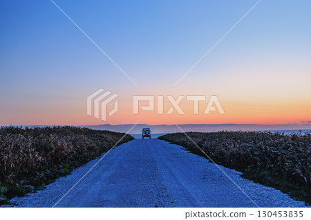 A white road at dusk, a straight road leading to the sea 130453835