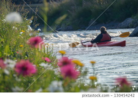 Experience the serene beauty of a woman kayaking on a river surrounded by colorful wildflowers on a sunny summer day Experience the serene beauty of a woman kayaking on a river surrounded by colorful wildflowers on a sunny summer day 130454242