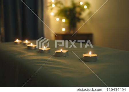 Flickering candles create a cozy spa atmosphere on a massage table. The gentle aroma adds to the relaxing ambiance for a peaceful treatment 130454494