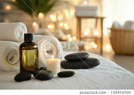 Relaxing spa treatment setting with burning candle, towels and massage oil on blurred background 130454500