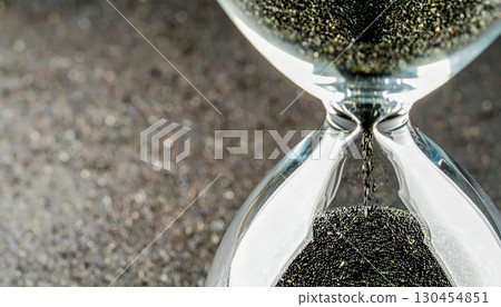 Close up enchanted hourglass with falling black sand symbolizing inevitable passage of time and mysterious Halloween aura Close up enchanted hourglass with falling black sand symbolizing inevitable passage of time and mysterious Halloween aura 130454851