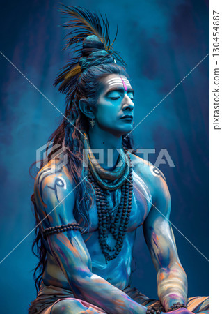 Man with blue body paint and traditional clothing is posing as the Hindu god Shiva, meditating with his eyes closed 130454887