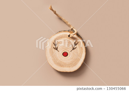Christmas toy made of decorative wooden slice with ornament on blue background. Handmade hobby. DIY. Nature material. Xmas decoration. Eco friendly. Zero waste. Sustainable gifts. View from above. 130455066