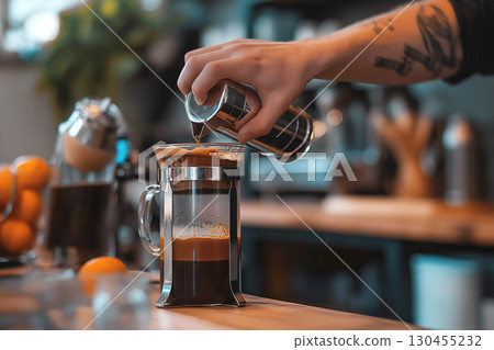 Barista is making a cup of coffee using a french press, pouring coffee in a glass server 130455232
