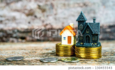 Small toy house on golden coins symbolizing savings, investment, mortgage, and economic security in finance concept 130455543