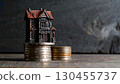Miniature haunted house on stacked coins symbolizing spooky real estate investment and Halloween finance concept. 130455737