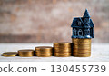 Small haunted house model placed on stacked gold coins showing Halloween real estate finance concept. 130455739