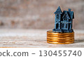 Creepy miniature haunted house sitting on coins, symbolizing spooky property and savings. 130455740