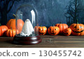 Halloween ghost inside a glass dome with glowing pumpkins and spooky dark background. 130455742