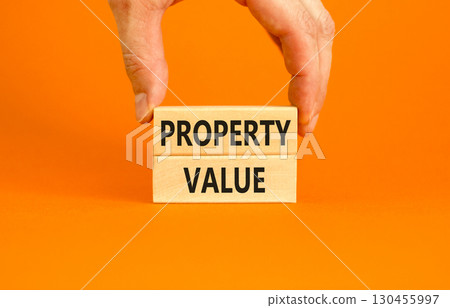 Property value symbol. Concept words Property value on beautiful wooden blocks. Beautiful orange table orange background. Businessman hand. Business property value concept. Copy space. 130455997