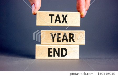 Tax year end symbol. Concept words Tax year end on beautiful wooden blocks. Beautiful grey background. Businessman hand. Business tax year end concept. Copy space. 130456030