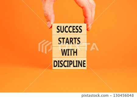 Success starts with discipline symbol. Concept words Success starts with discipline on beautiful wooden blocks. Beautiful orange background. Business success starts with discipline concept. Copy space Success starts with discipline symbol. Concept words Success starts with discipline on beautiful wooden blocks. Beautiful orange background. Business success starts with discipline concept. Copy space 130456048