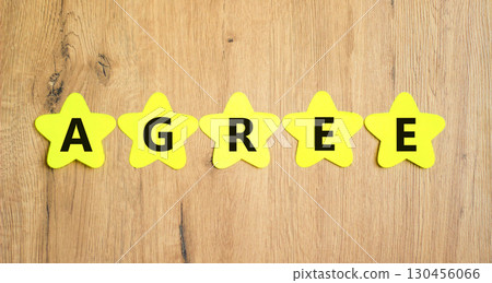 Agree symbol. Concept word Agree on beautiful yellow paper stars. Beautiful wooden table wooden background. Business agree concept. Copy space. 130456066