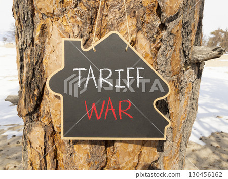 Trade tariff war symbol. Concept word Tariff war on beautiful black blackboard. Beautiful old pine tree background. Black blackboard. Business trade tariff wars concept. Copy space. 130456162