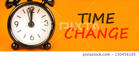 Time change symbol. Concept word Time change on beautiful orange paper. Beautiful black alarm clock. Beautiful orange paper background. Business time change concept. Copy space. 130456185