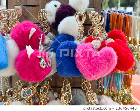 Plush heart keychains in bright colors displayed on a rack. Fashion accessory, retail decoration, textile charm and seasonal gift concept. 130456446