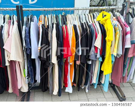 Close view of colorful t-shirts hanging in street retail market. Shopping, fashion, and lifestyle consumer concept in outdoor commerce. Close view of colorful t-shirts hanging in street retail market. Shopping, fashion, and lifestyle consumer concept in outdoor commerce. 130456587
