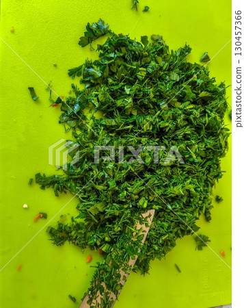 Chopped green parsley herbs on cutting board ready for cooking use and garnish Chopped green parsley herbs on cutting board ready for cooking use and garnish 130457366