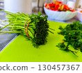 A fresh bundle of parsley with stems and leaves on a green cutting board, prepared in the kitchen for use in salads, soups, and other homemade healthy dishes with natural ingredients. 130457367