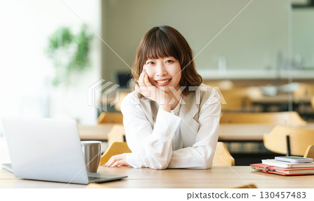 一位女商人靠在她的手肘上微笑 一位女商人靠在她的手肘上微笑 130457483