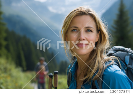 The Strength of a Woman's Spirit: A Confident and Happy Hiker Smiling at the Camera in a Lush Mountain Landscape. 130457874