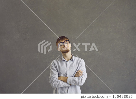 Portrait of a serious caucasian young man with a pensive expression on a gray background. Portrait of a serious caucasian young man with a pensive expression on a gray background. 130458055